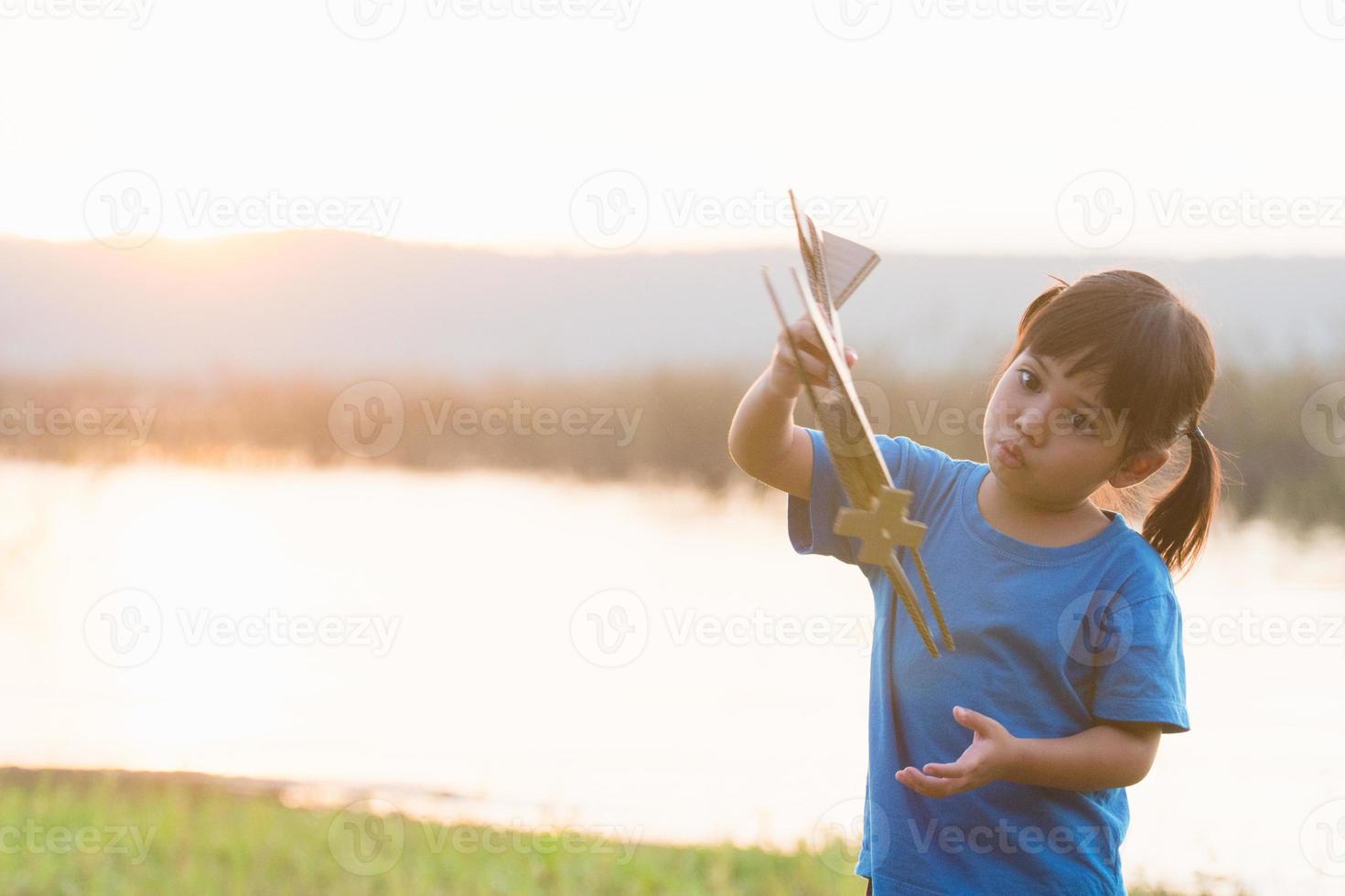 dreams of flight child playing with toy airplane against the sky at sunset photo