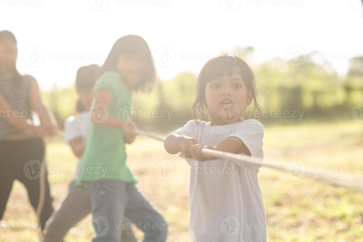 Children playing tug of war at the park on sunsut photo