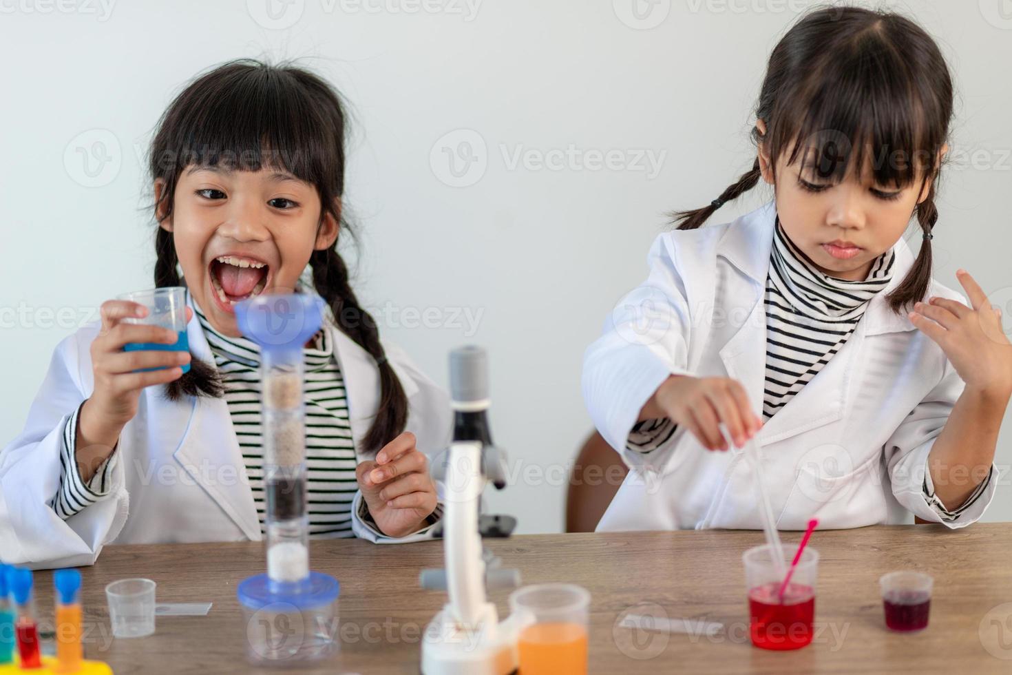 education, science, chemistry and children concept - kids or students with test tube making experiment at school laboratory photo