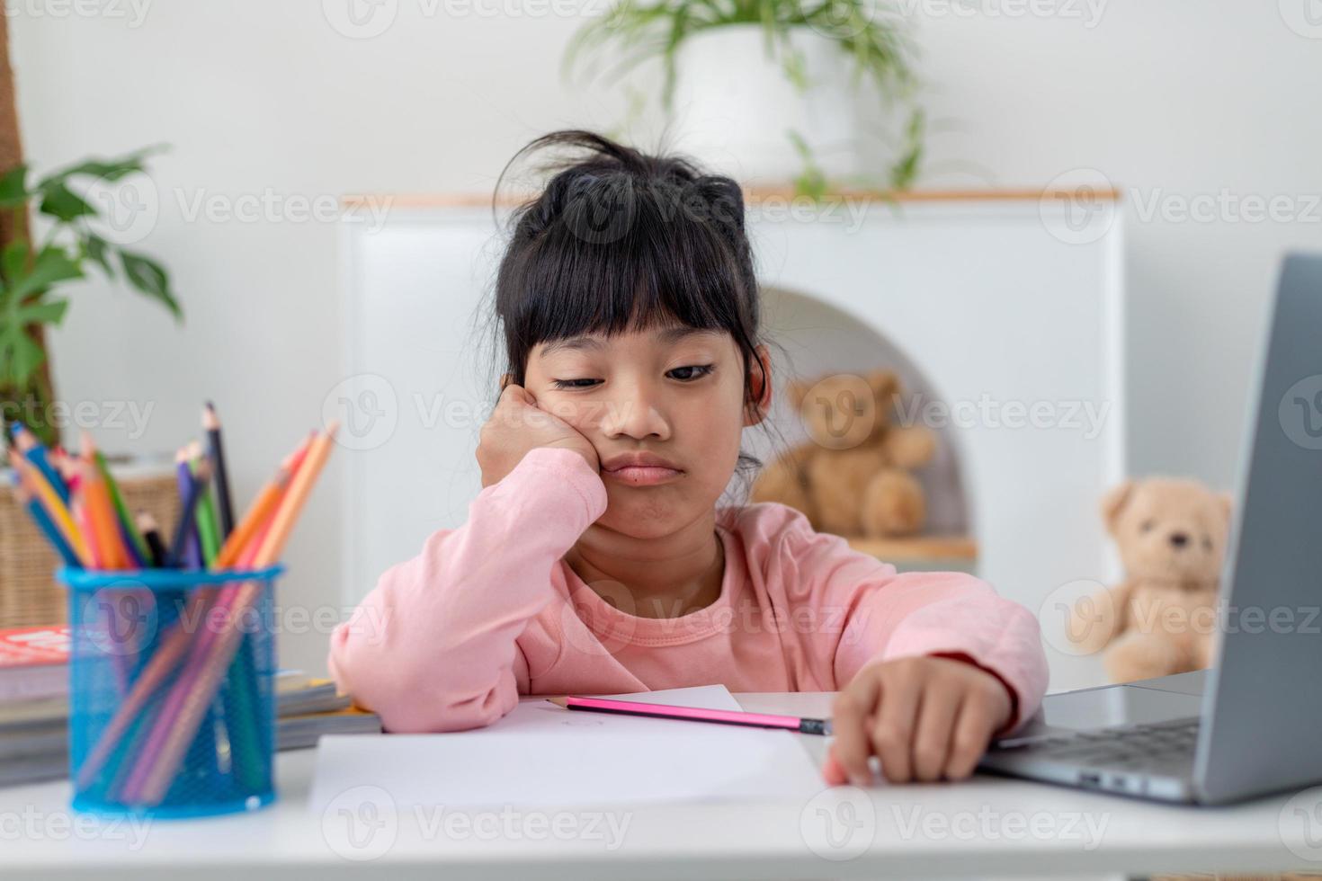 Unhappy little Caucasian girl child sit at table at home feel lazy unmotivated doing homework assignment. Upset distressed small 7s kid prepare school task, learn study with books. Education concept. photo