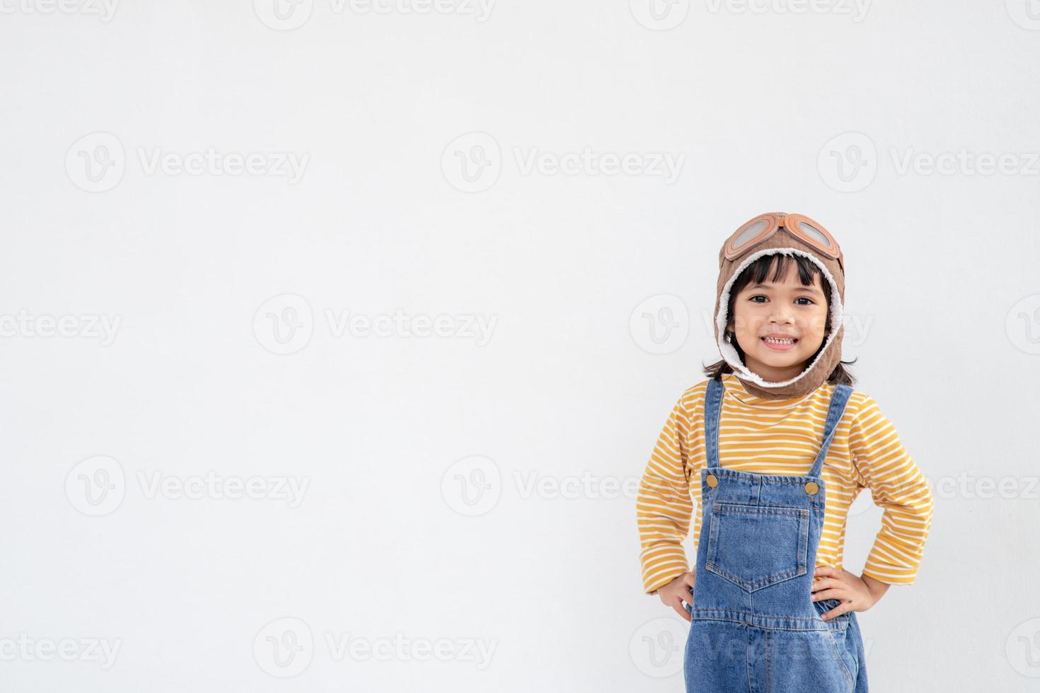 dreams of flight little child girl playing with a pilot hat on white background photo