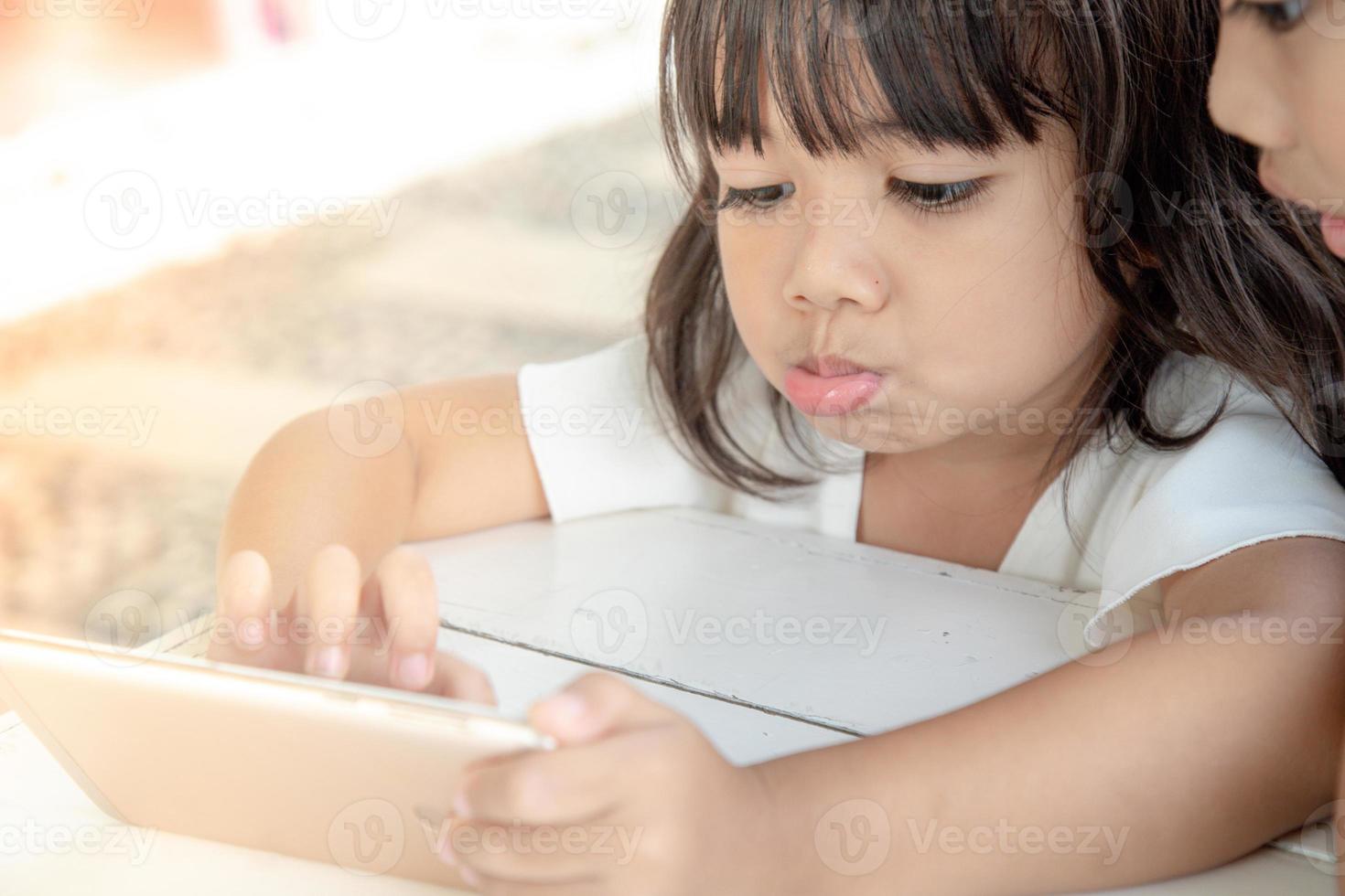 Little Asian girl using smart phone at cafe. Natural light outdoor lifestyle. photo