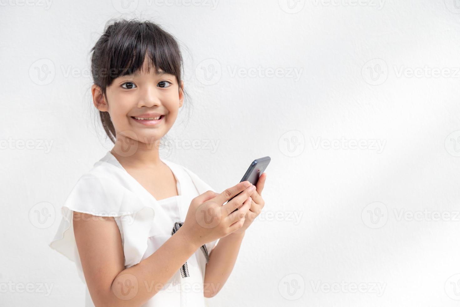 Photo of a little girl using a mobile phone isolated over white background