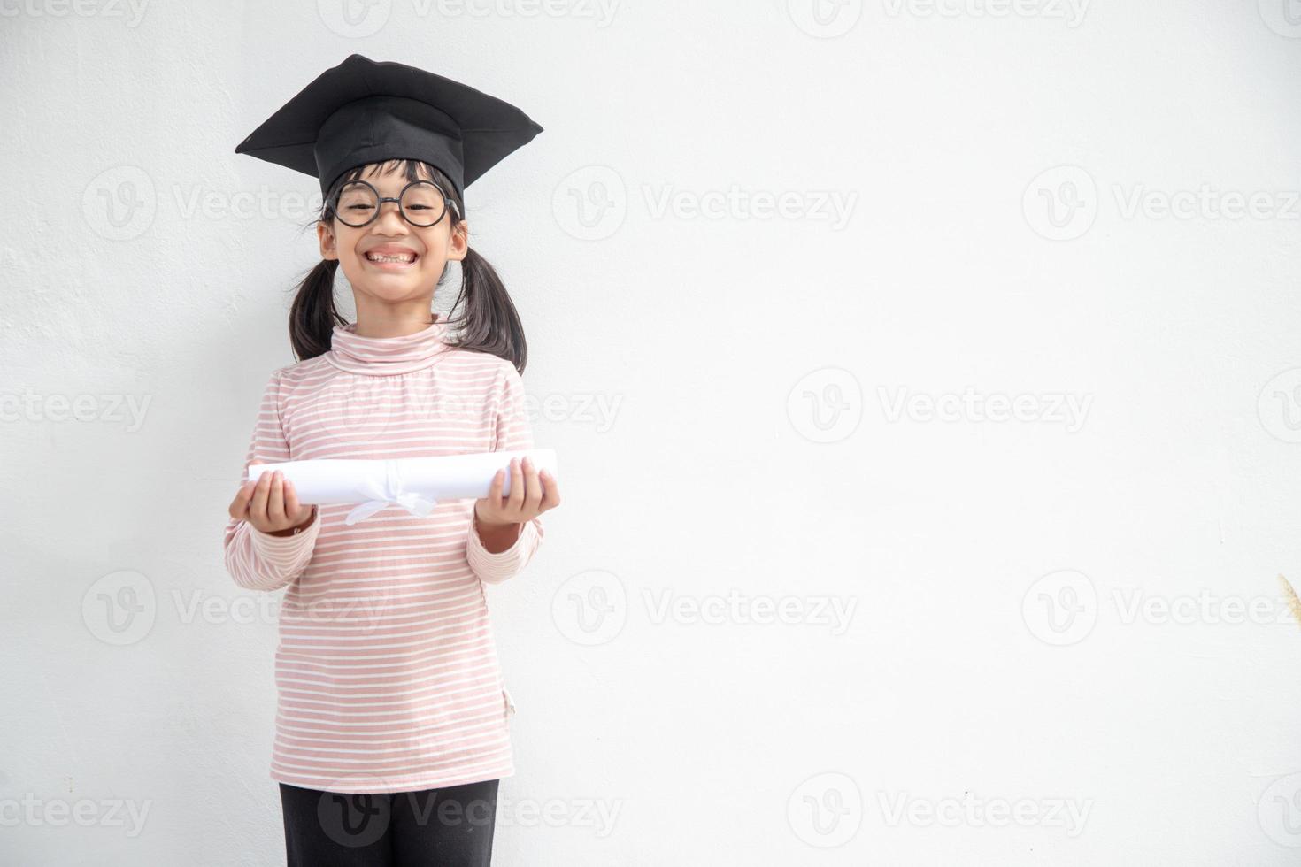 Happy Asian school kid graduate in graduation cap photo
