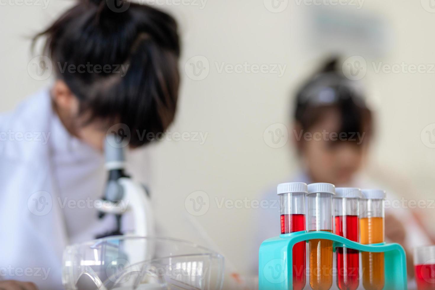 education, science, chemistry and children concept - kids or students with test tube making experiment at school laboratory photo