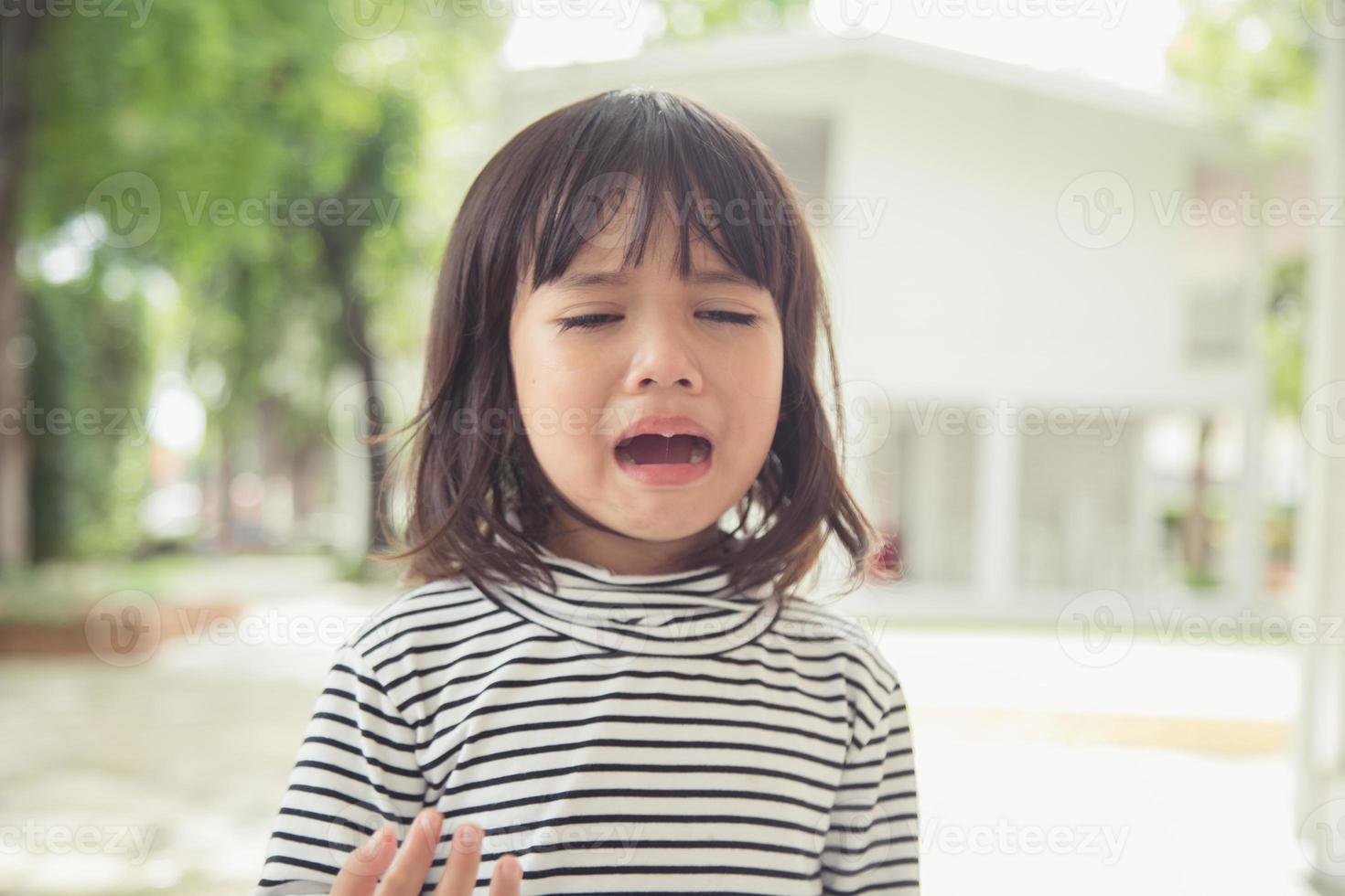 Portrait of Asian crying little girl with little rolling tears weeping emotion, hurt in pain fit drops cheek. Young crying panic drama Asian toddler. photo