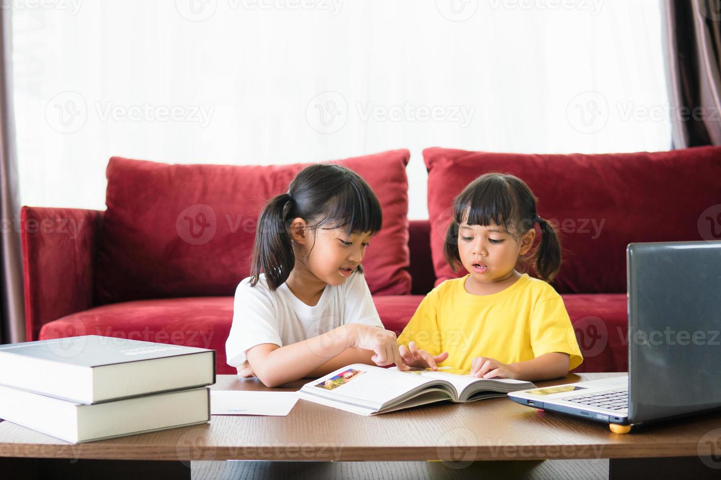 Two asian child girl students study online with teacher by video call together. Siblings are homeschooling with computer laptop during quarantine due to Covid 19 pandemic. photo