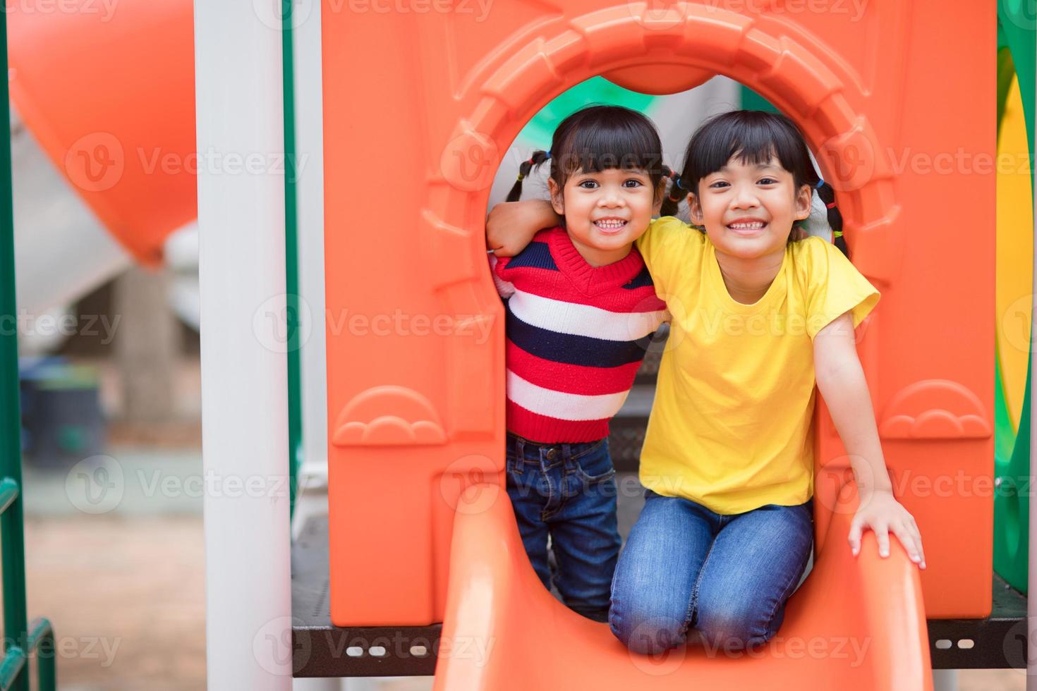 lindas niñas hermanos divirtiéndose en el patio de recreo al aire libre en un día soleado de verano foto
