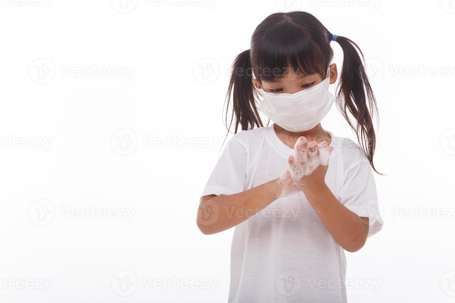 niño lavándose las manos y mostrando las palmas jabonosas sobre fondo blanco foto