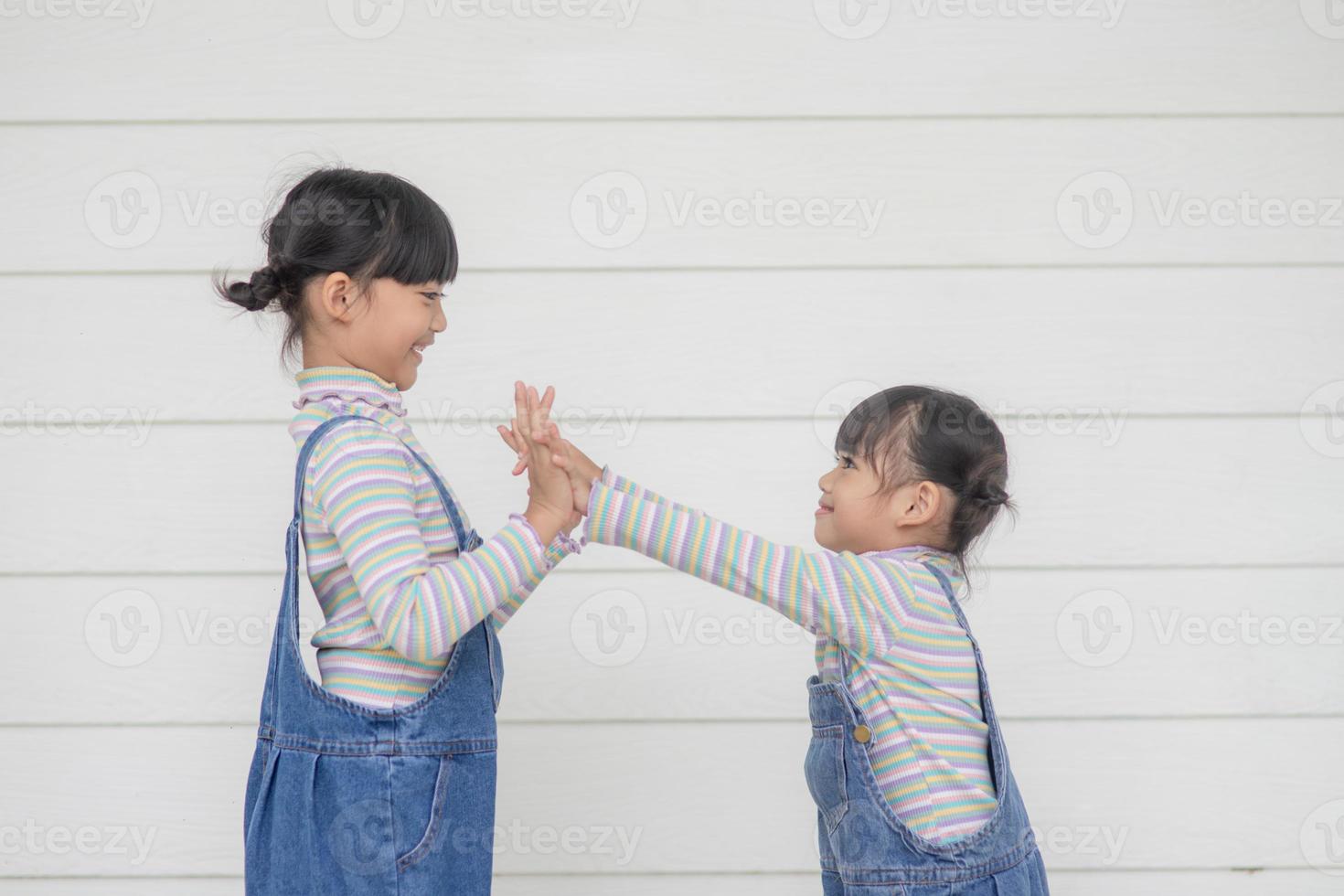 Two children a standing together and hold their hands up on a white background photo