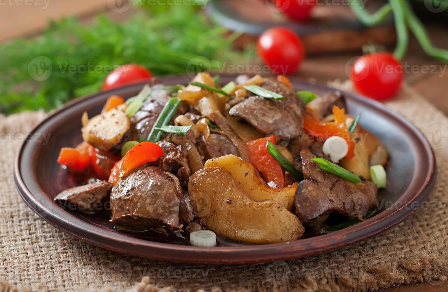 Roast chicken liver with vegetables on wooden background photo