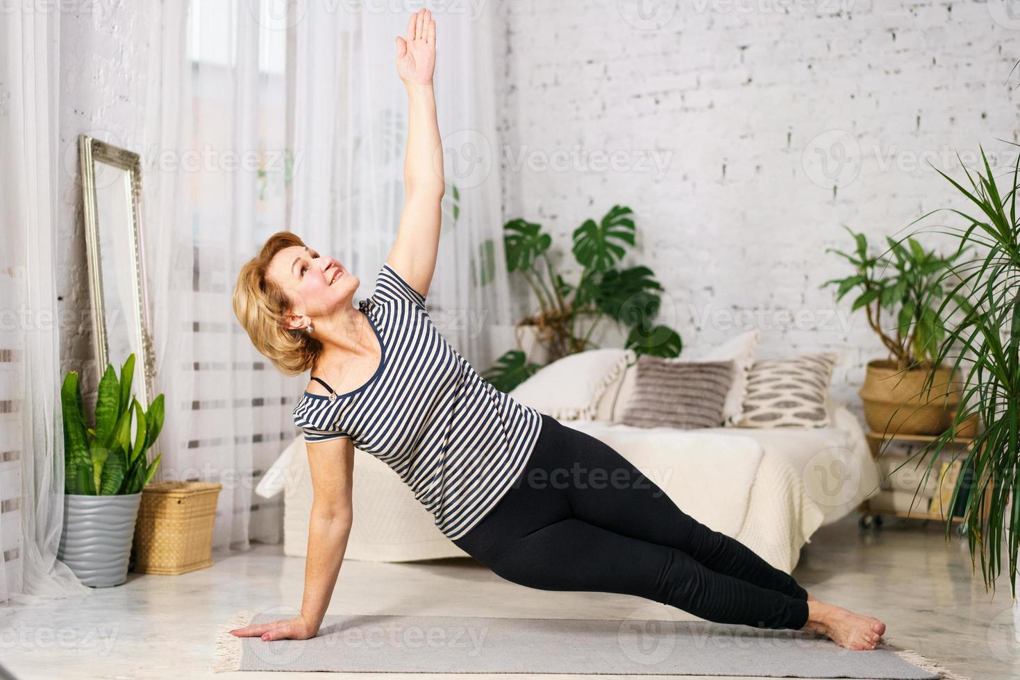 Mature woman doing sports on mat at home photo