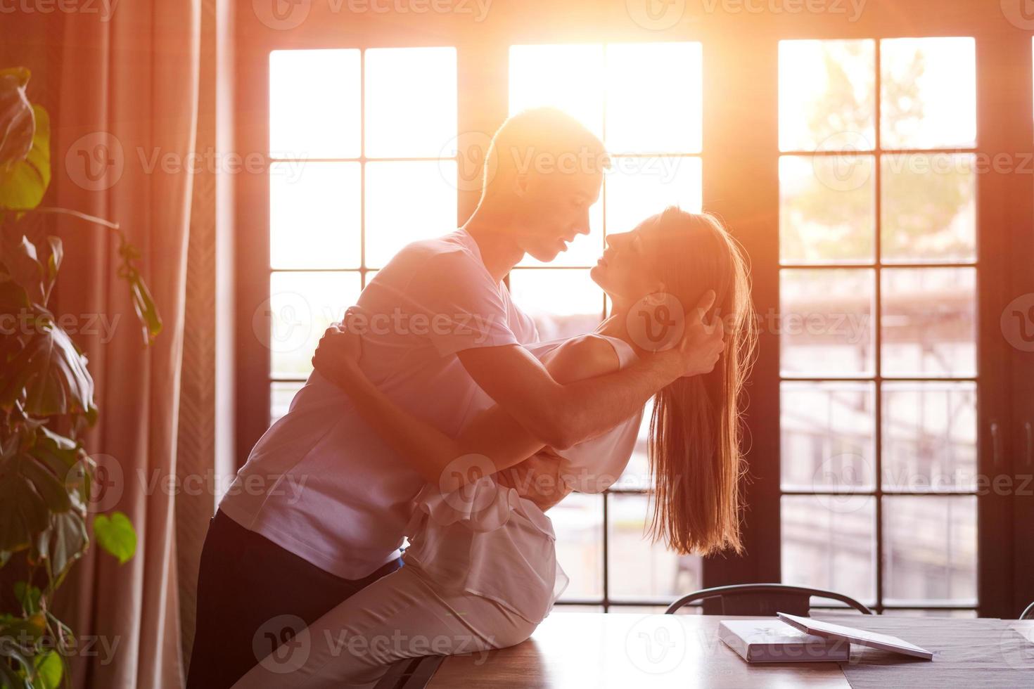 joven pareja apasionada en la habitación contra la ventana de fondo, la chica está sentada foto