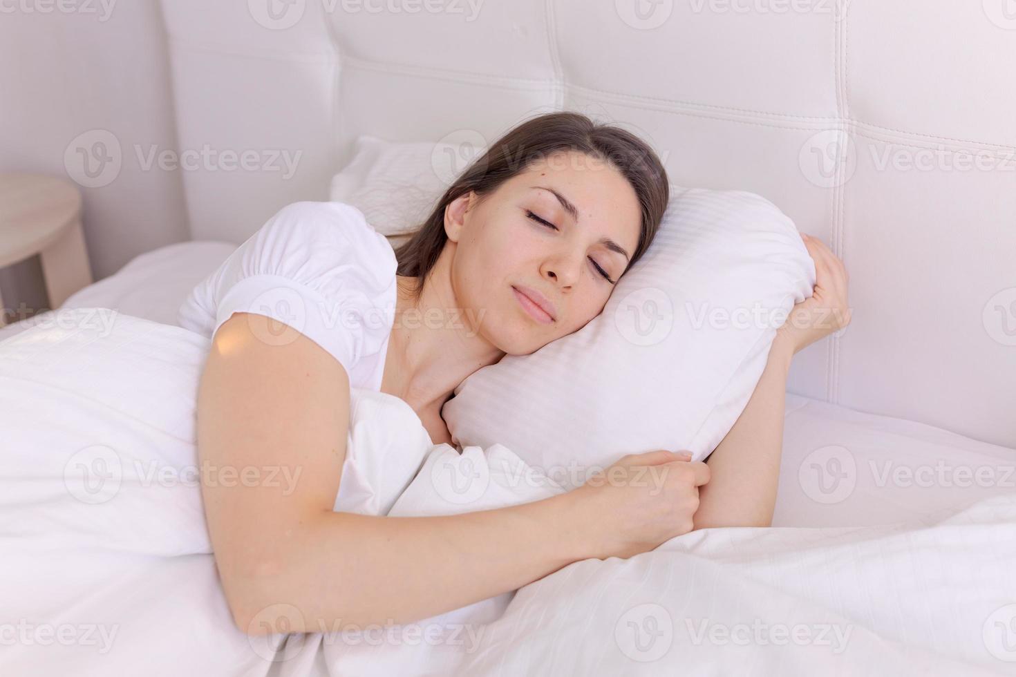 Photograph sleeping young woman lies in bed with her eyes closed on a white photo