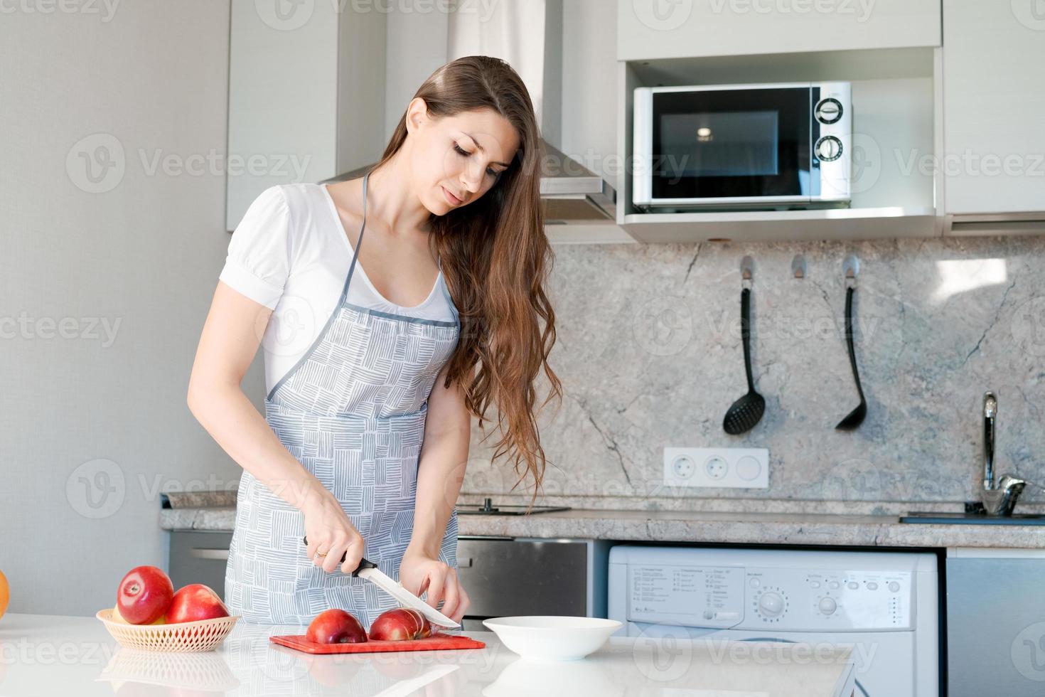 Young Woman prepares and cuts red apple on cutting board. Cooking healthy food. photo