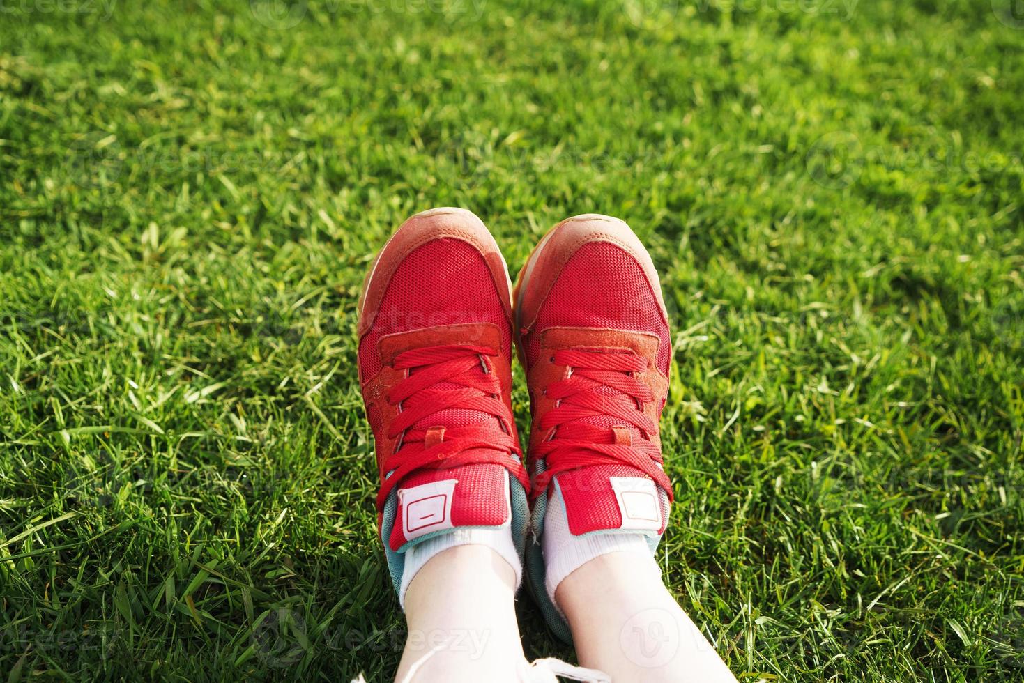 female legs in sneakers on a background of green grass photo