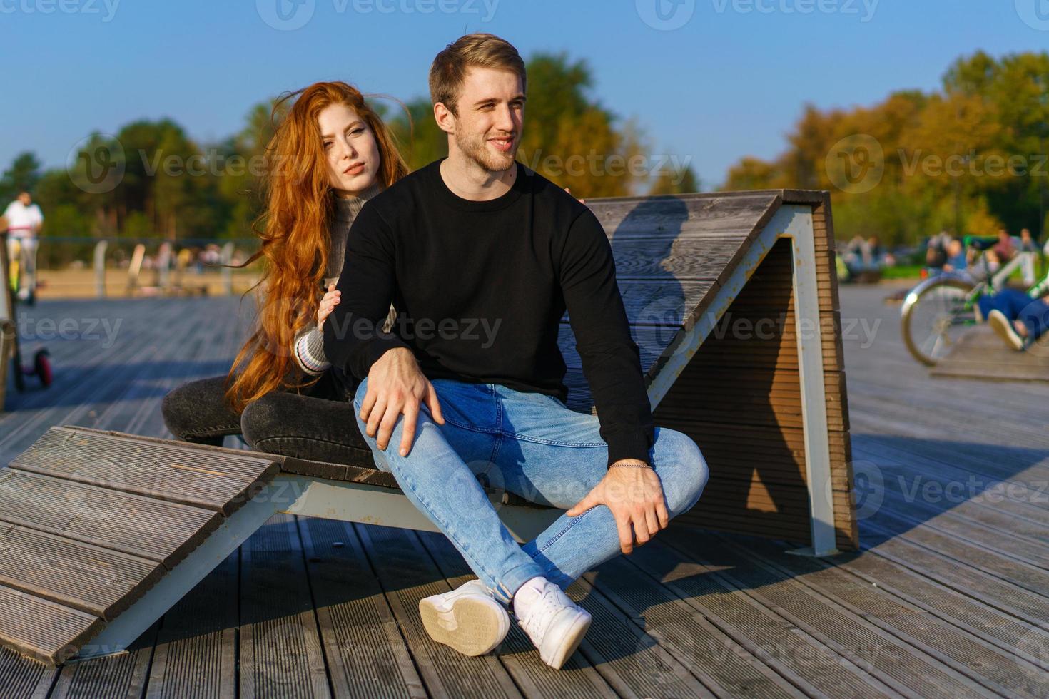 happy couple guy and girl are sitting on a wooden deck hugging photo