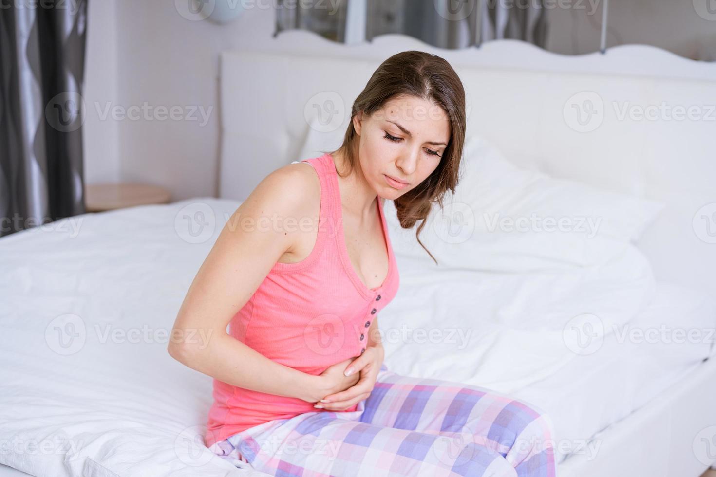 Young beautiful caucasian woman with painful expression holding her stomach photo