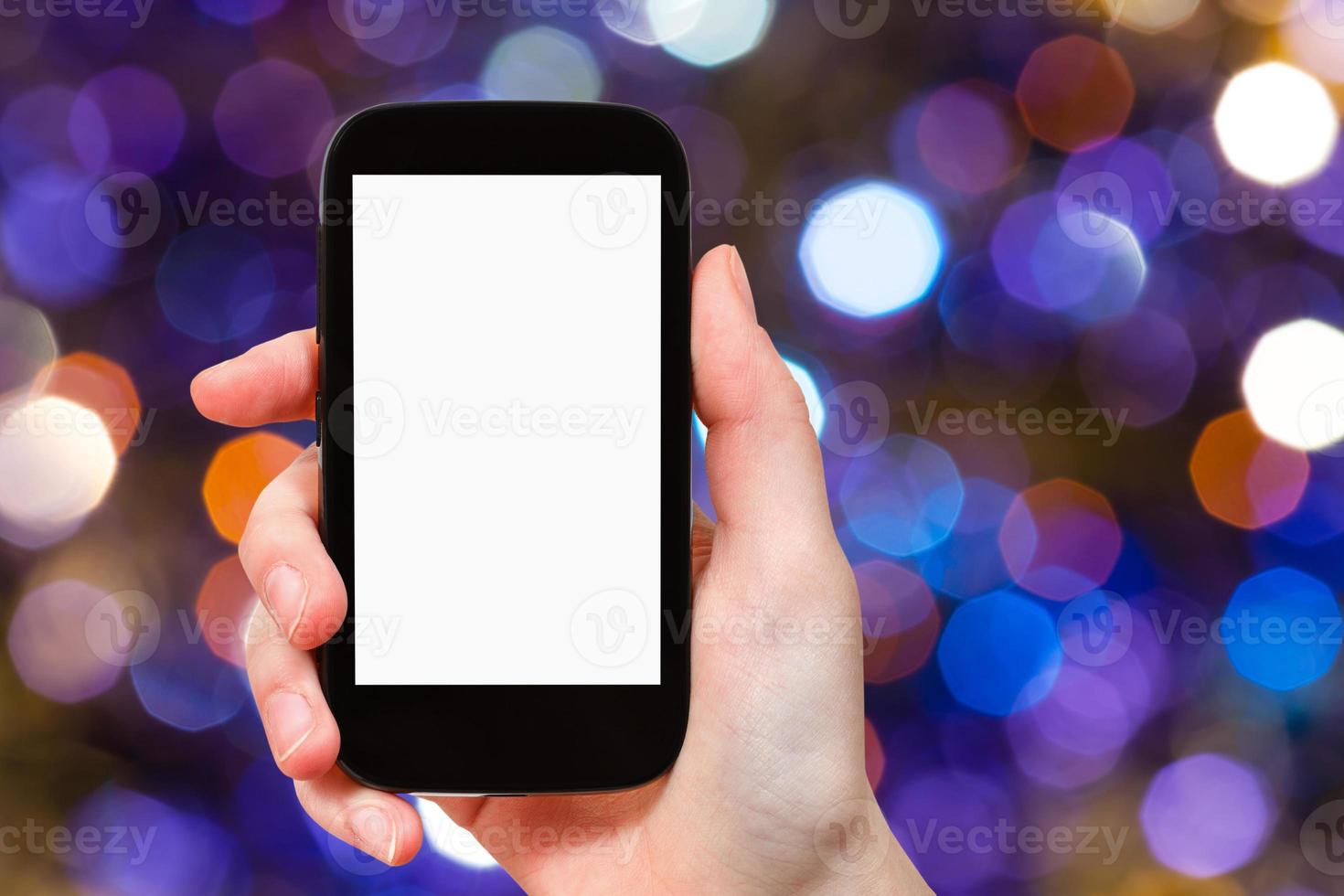 hand with smartphone on dark violet background photo