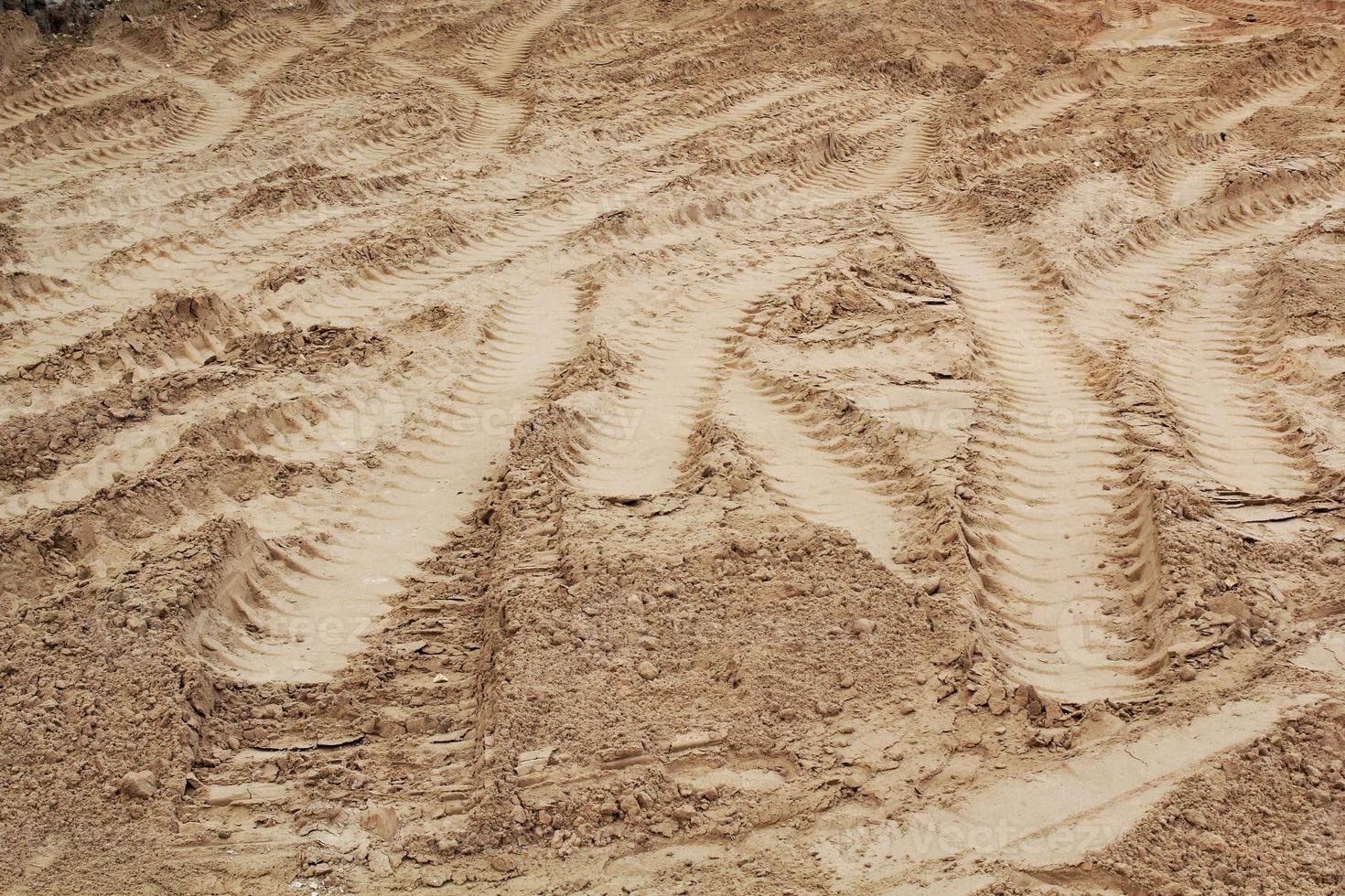 Tire track mark lines shape on dry sand background. Trail tyre imprint from heavy machinery. Vehicle shape. Road construction site backdrop concept. Trace of wheel pattern on mud. Nature texture. photo