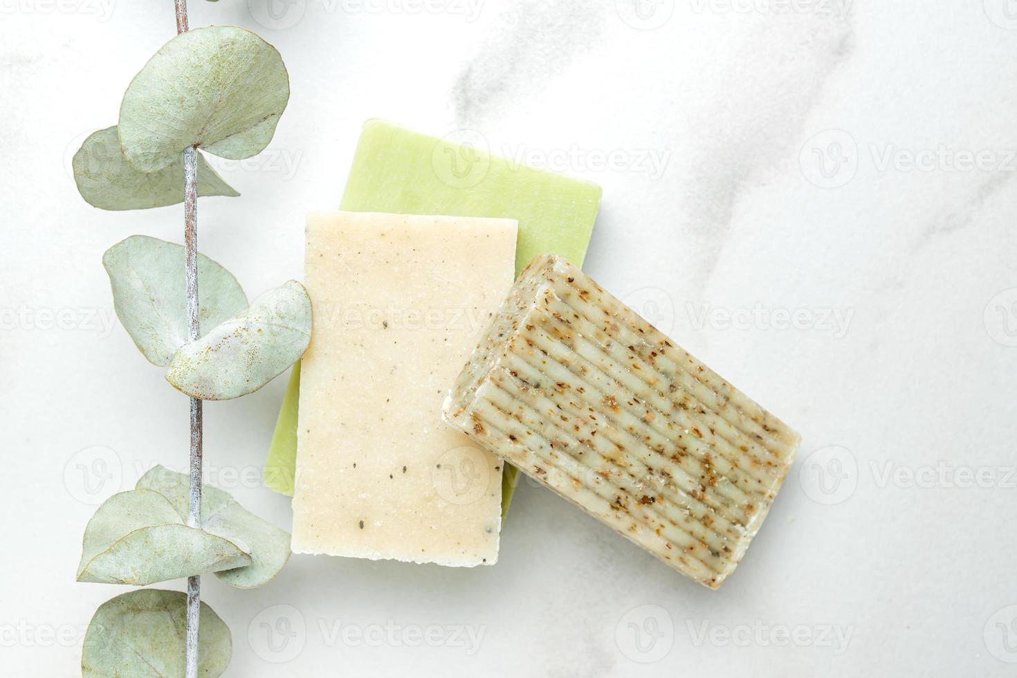 Zero waste cosmetics concept. Flat lay, top view of natural, organic solid handmade soap and eucalyptus plant near it on marble background photo