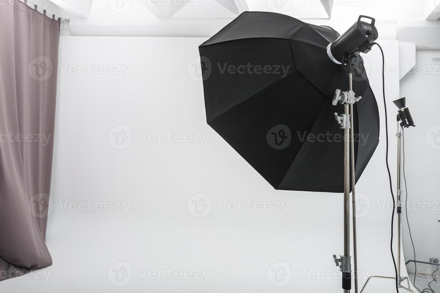 interior of bright space of photo studio with large white cyclorama with lighting equipment