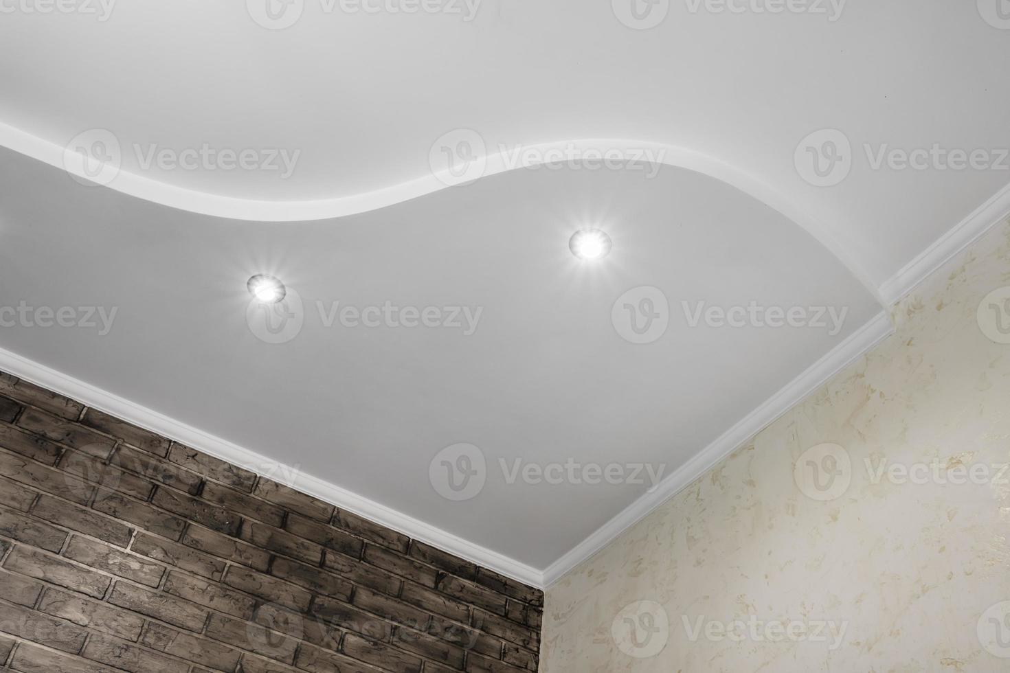 Detail of corner ceiling with intricate crown molding. Suspended ceiling and drywall construction in empty room in apartment or house. Stretch ceiling white and complex shape. photo