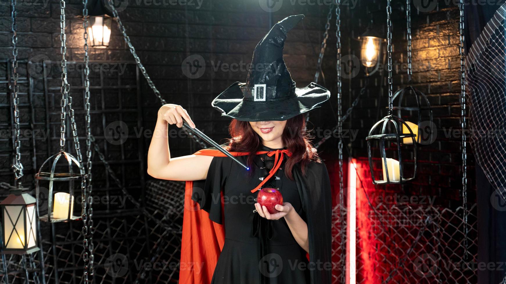 Halloween Girl wearing witch costume with a hat using magic wand with apple for happy in halloween day photo