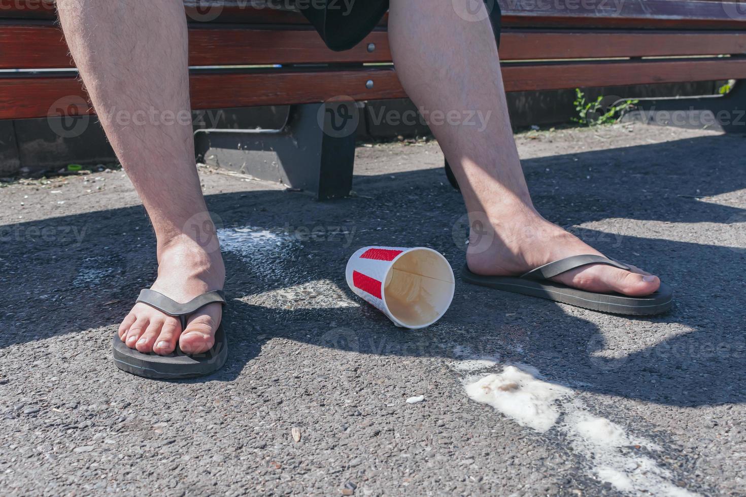 A teenager dropped a paper cup with a hot drink under his feet photo
