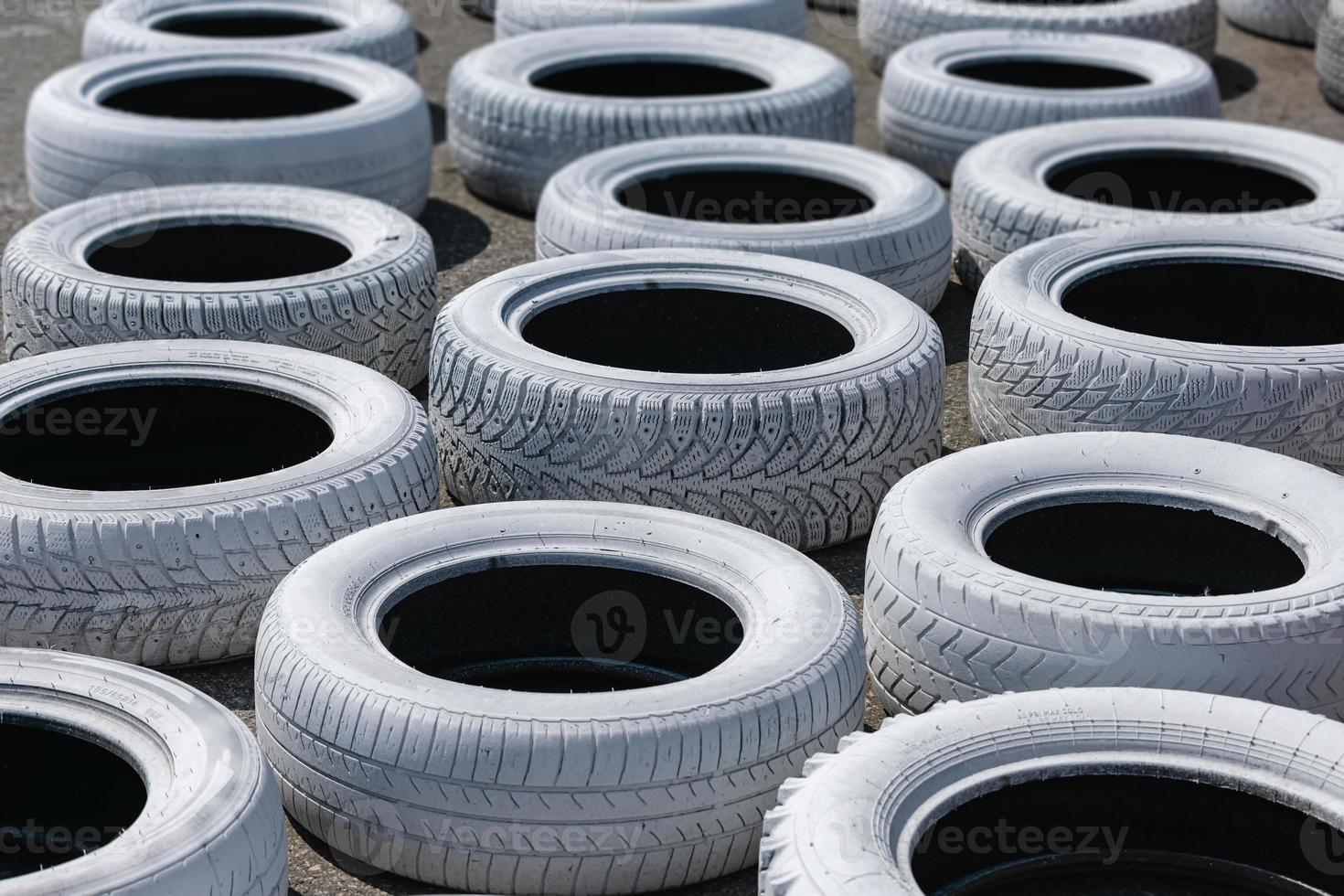 Old used car tires, painted bright white and installed on the race track for safety photo