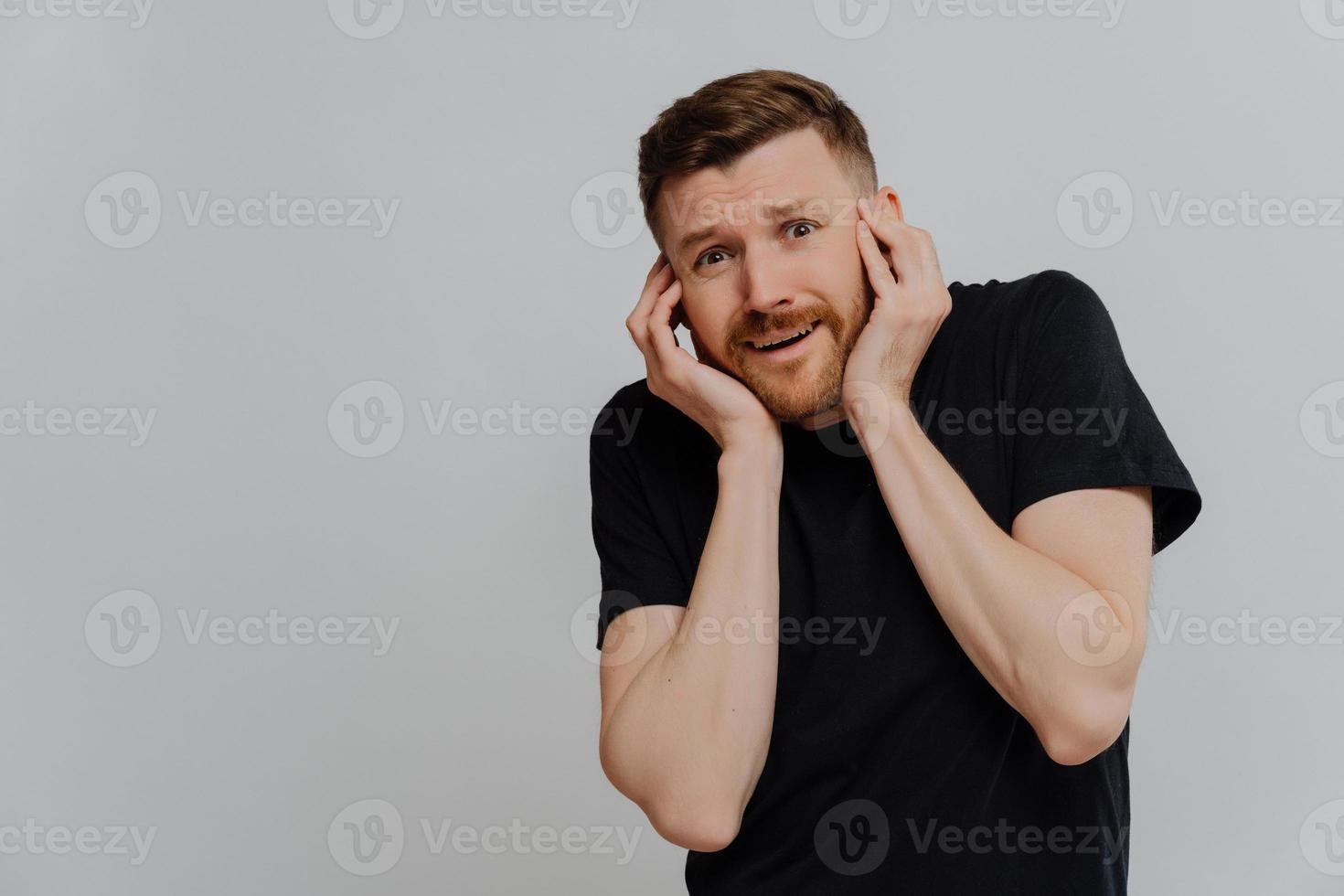 Young nervous man with horrified facial expression being afraid photo