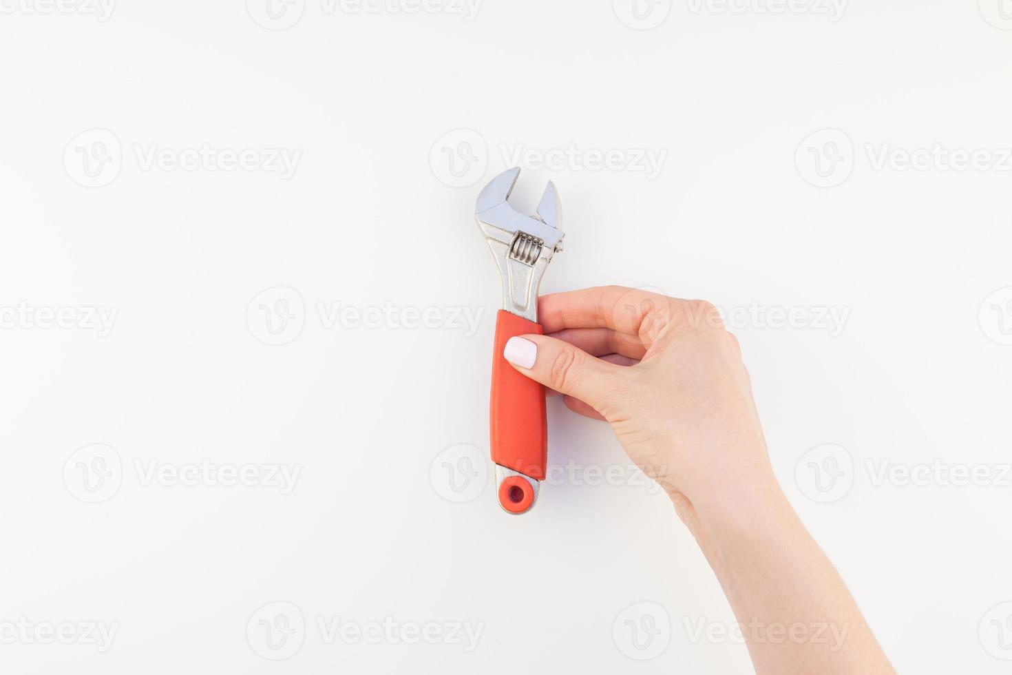 Female hand holding spanner on white background photo