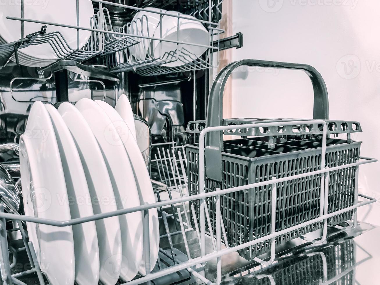 Open dishwasher machine with white clean dishes photo