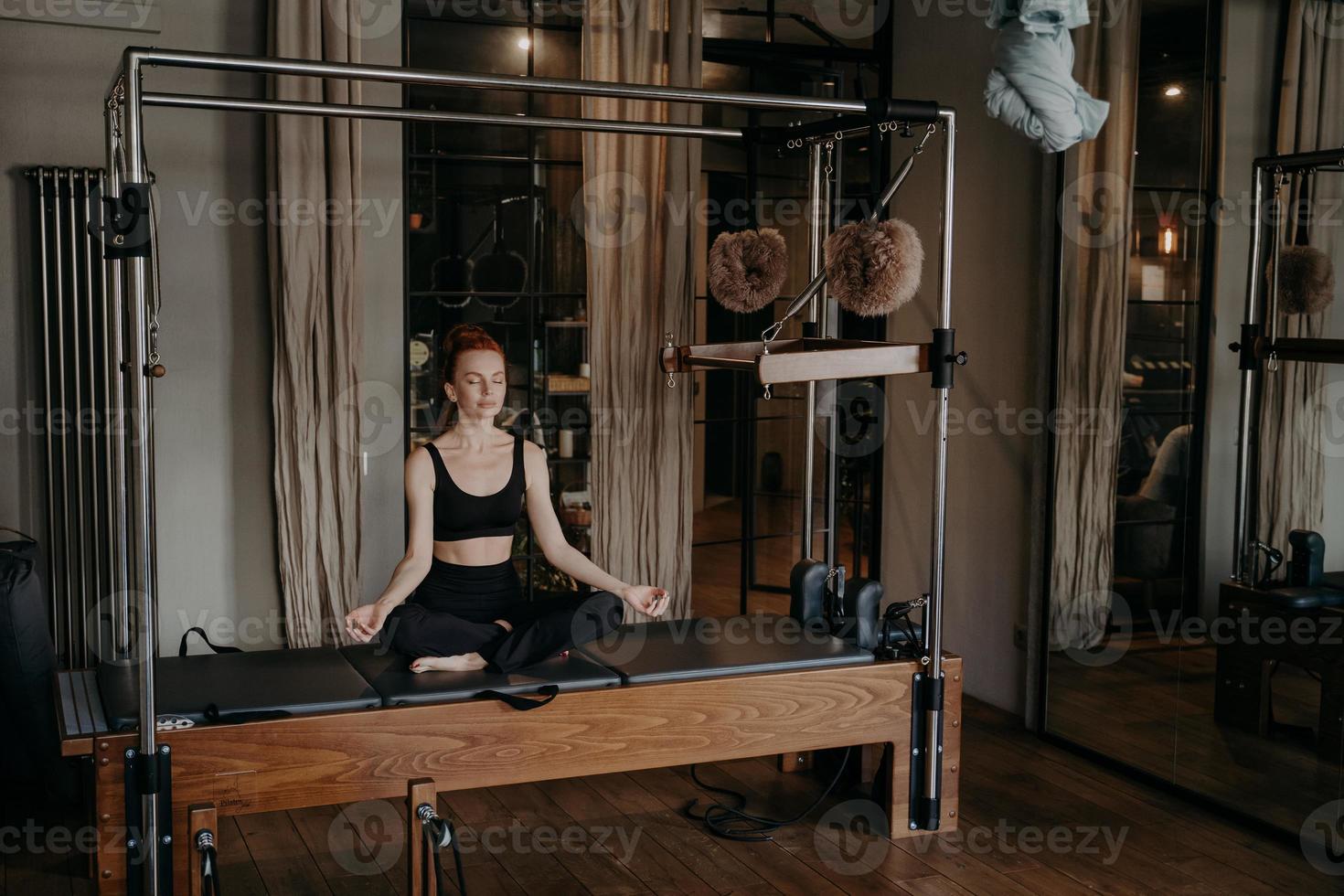 mujer joven en forma sentada en posición de loto en la mesa de trapecio foto