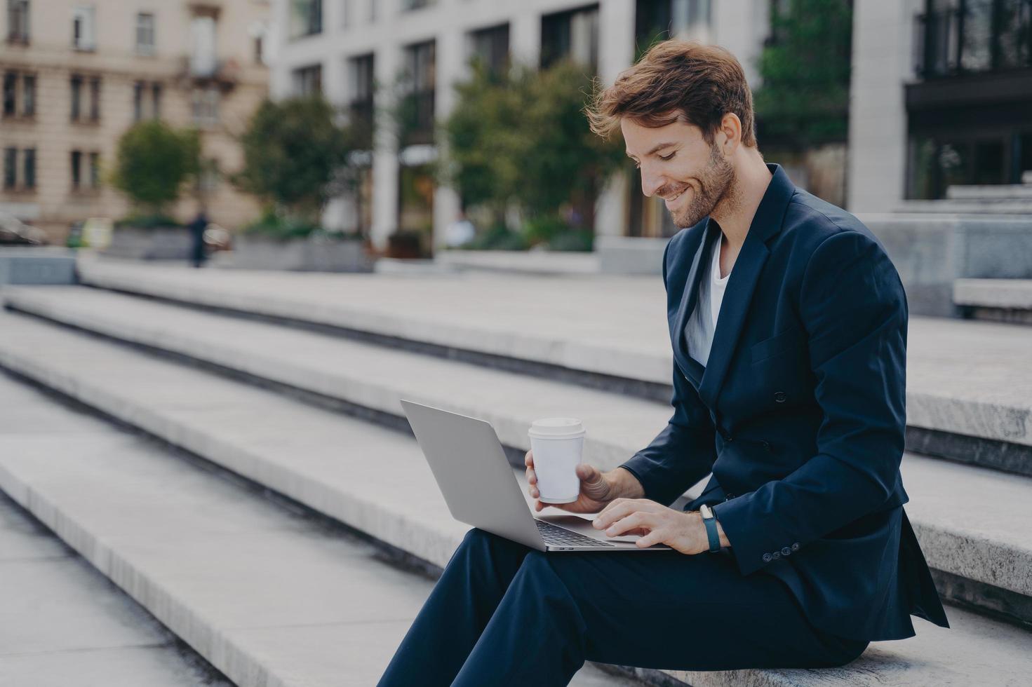 joven hombre de negocios satisfecho con traje elegante sentado en