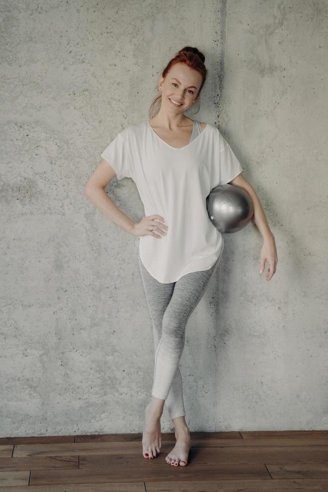 Happy female with small pilates ball resting after workout in studio photo