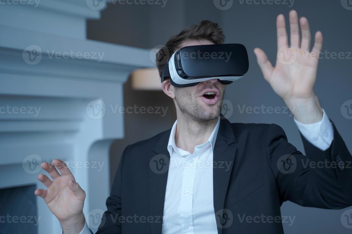 Man entrepreneur in formal suit sitting at home office while testing VR goggles photo
