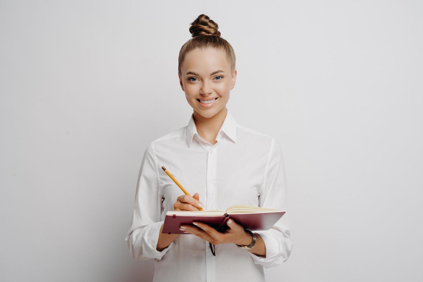 profesional de negocios con camisa blanca escribiendo ideas en un cuaderno foto