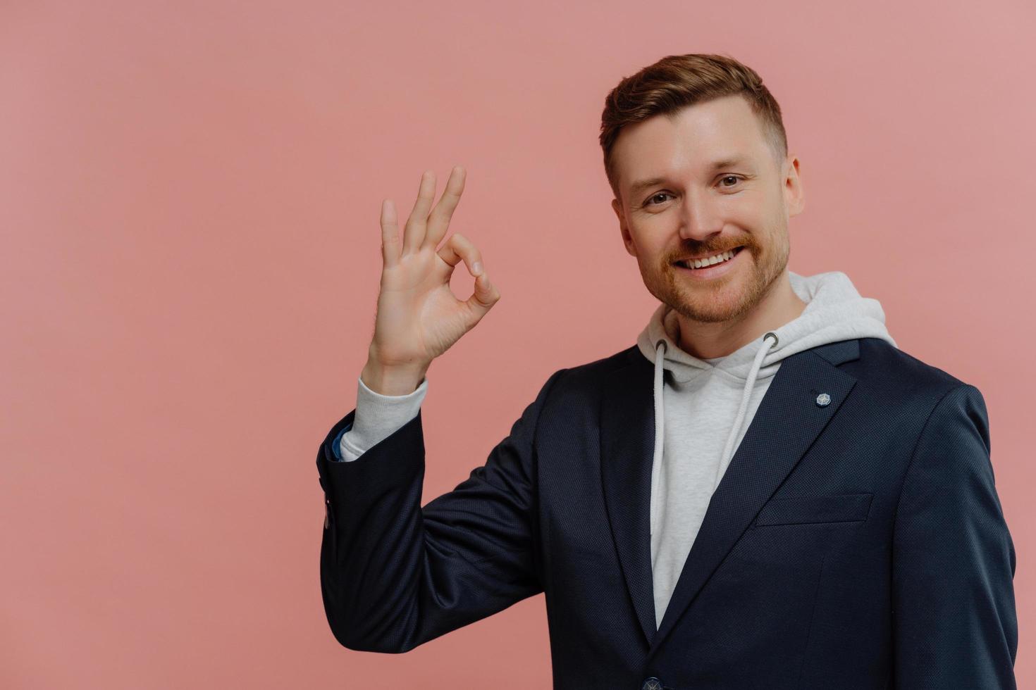 Cheerful man showing ok sign and smiling isolated over pink wall photo