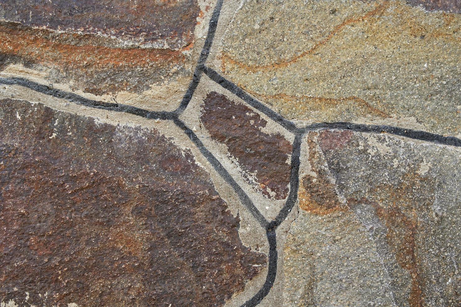 The texture of the wall of granite stones of different shapes and color. photo