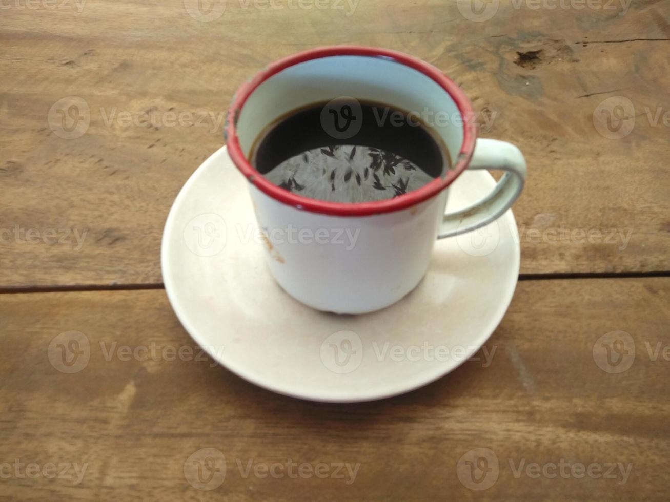 una taza de café negro sentada en una mesa hecha de tablones de madera foto
