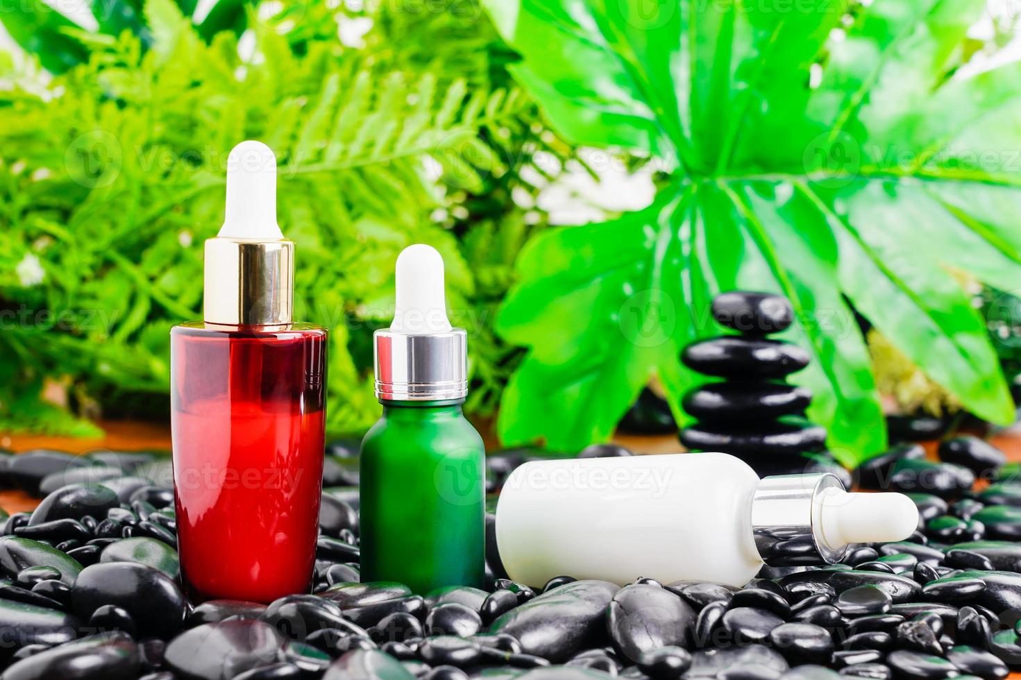 Cosmetic glass bottle for essential oils on black stone photo