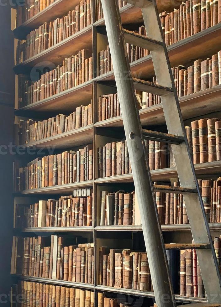 Old vintage books on a bookshelf with a ladder photo