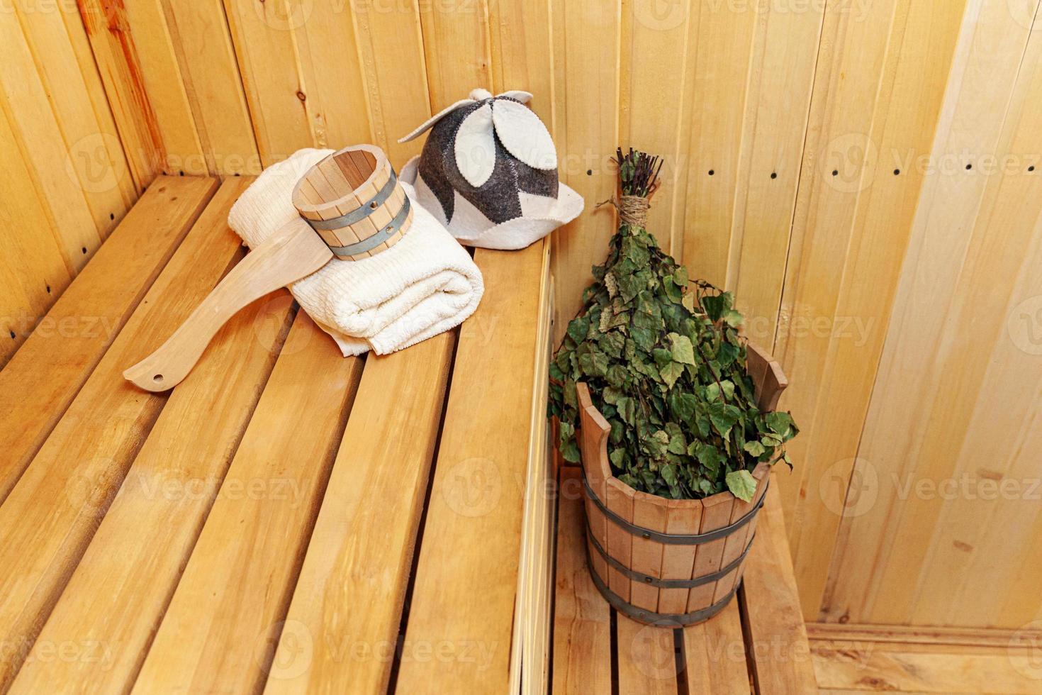 Interior details Finnish sauna steam room with traditional sauna accessories basin birch broom scoop felt hat towel. Traditional old Russian bathhouse SPA Concept. Relax country village bath concept. photo