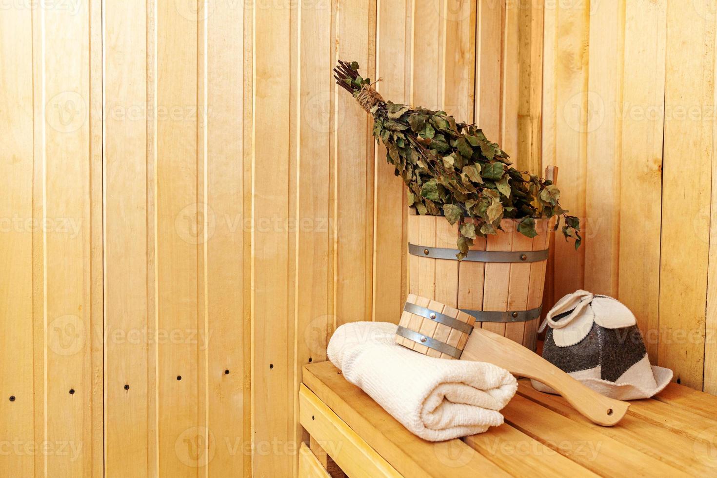 Interior details Finnish sauna steam room with traditional sauna accessories basin birch broom scoop felt hat towel. Traditional old Russian bathhouse SPA Concept. Relax country village bath concept. photo
