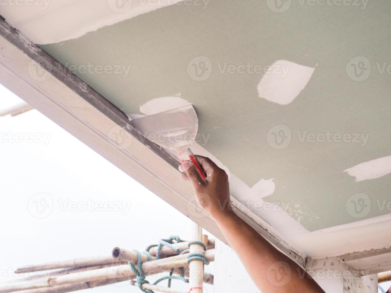 The ceiling worker is plastering the ceiling joints with high quality white gypsum plaster to keep the joints together. photo