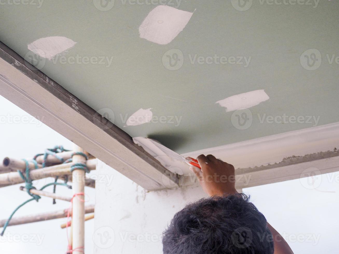 el trabajador del techo está enyesando las juntas del techo con yeso blanco de alta calidad para mantener juntas las juntas. foto