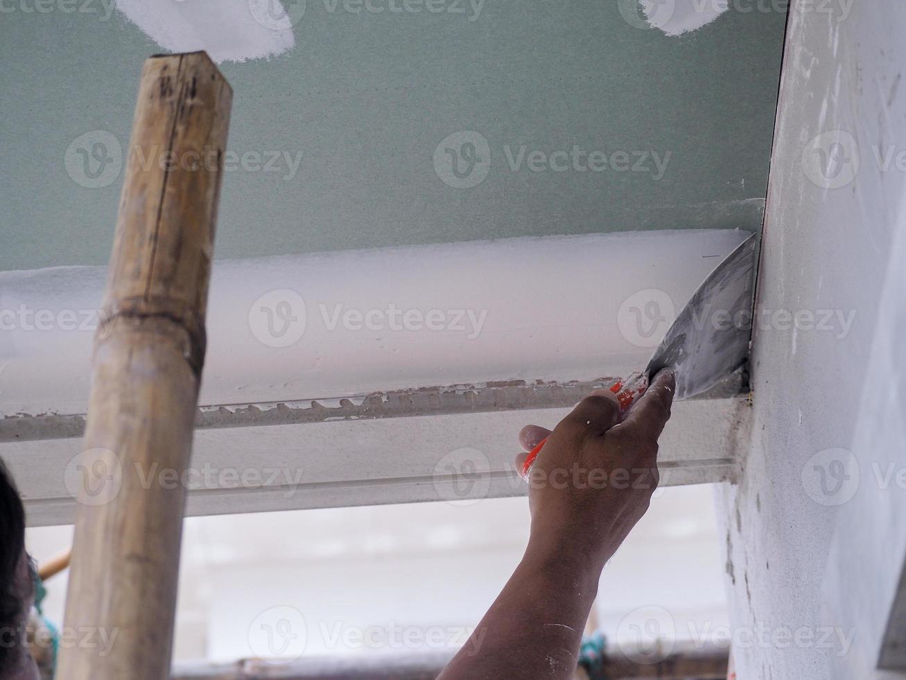 el trabajador del techo está enyesando las juntas del techo con yeso blanco de alta calidad para mantener juntas las juntas. foto