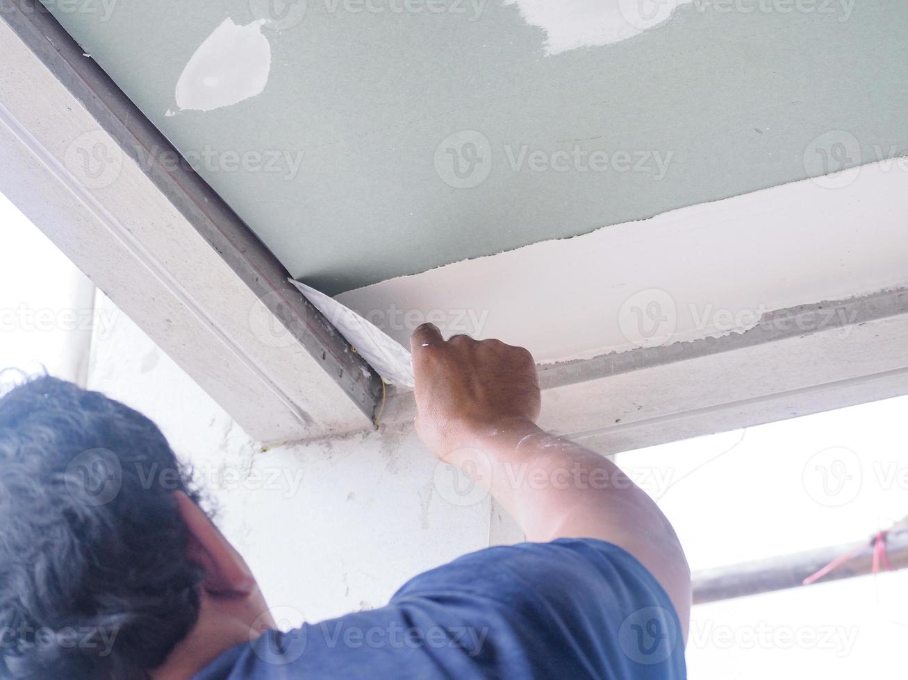 The ceiling worker is plastering the ceiling joints with high quality white gypsum plaster to keep the joints together. photo