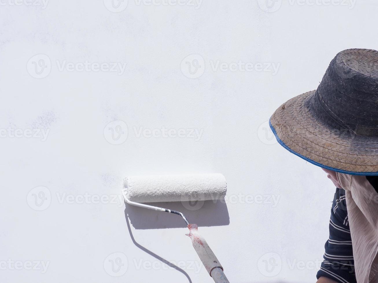 A worker is painting the walls of the house with a primer using a paint roller. photo